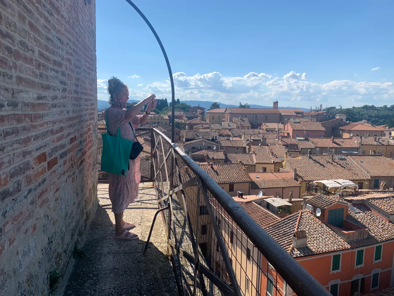 Woman standing on top of a bell tower in Chiusi, looking out over the rooftops and surrounding hills of the city.