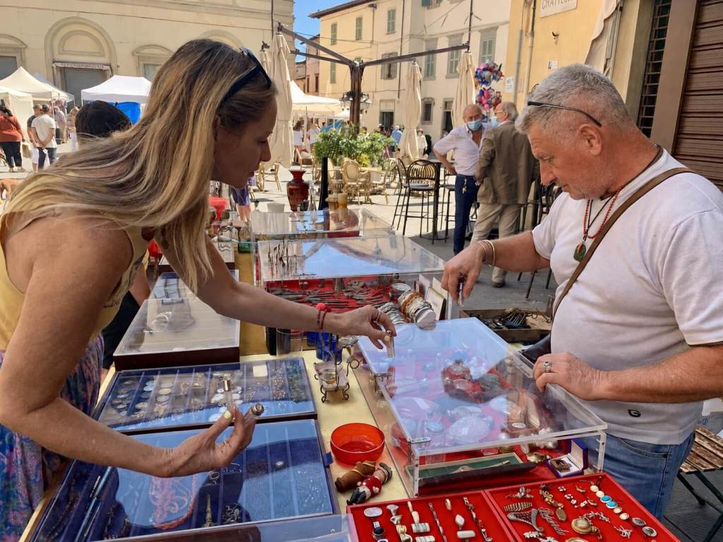 Antique-market stall displaying vintage jewellery and collectables in an Italian town square