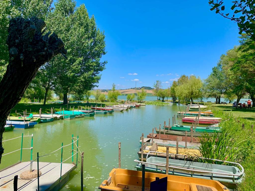 Fishing boats on Lake Chiusi in Tuscany with calm water and natural lakeside scenery