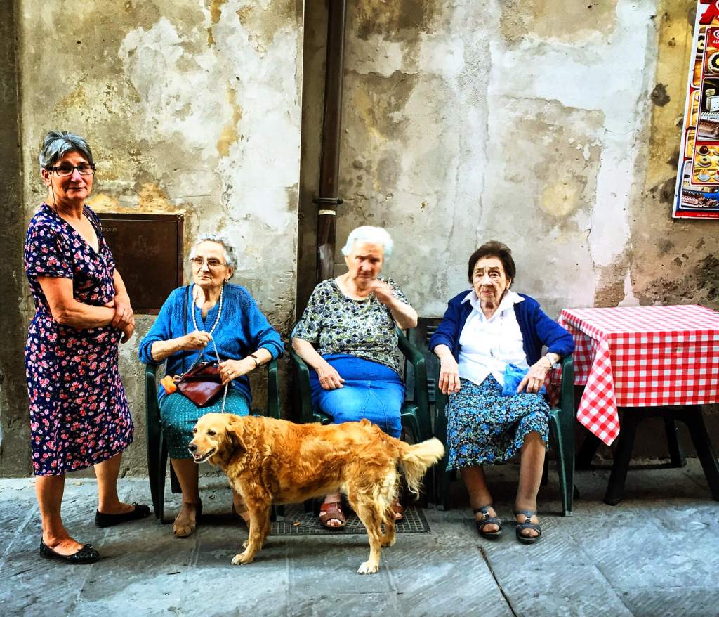 Women talking in a sunlit street in Cortona Italy