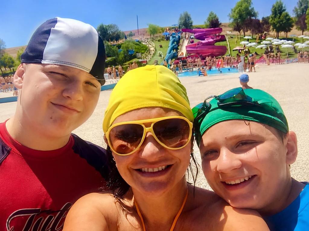 Family enjoying a sunny day at Tavernelle Water Park near Villa Gioiella, with colourful water slides and pools in the background.