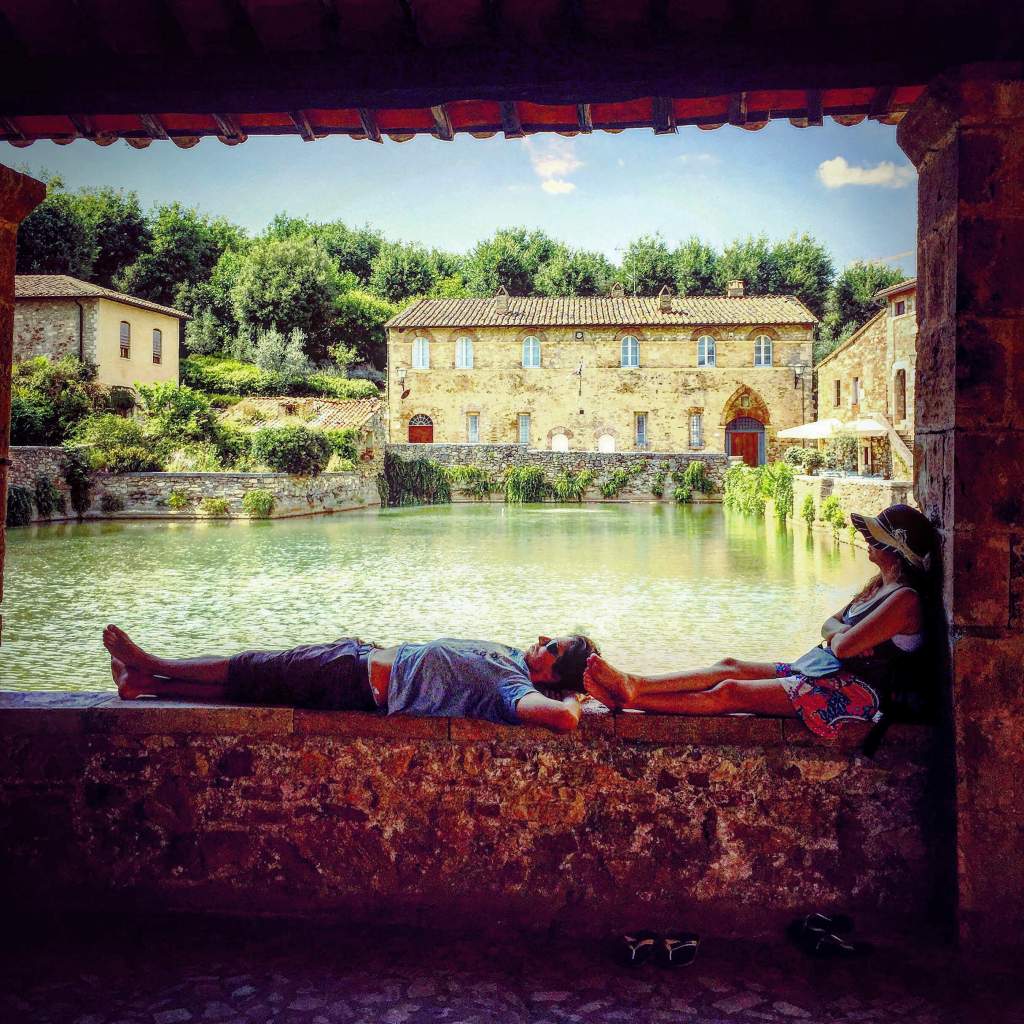 Visitors relaxing beside the historic thermal pool in Bagno Vignoni, Val d’Orcia, Tuscan